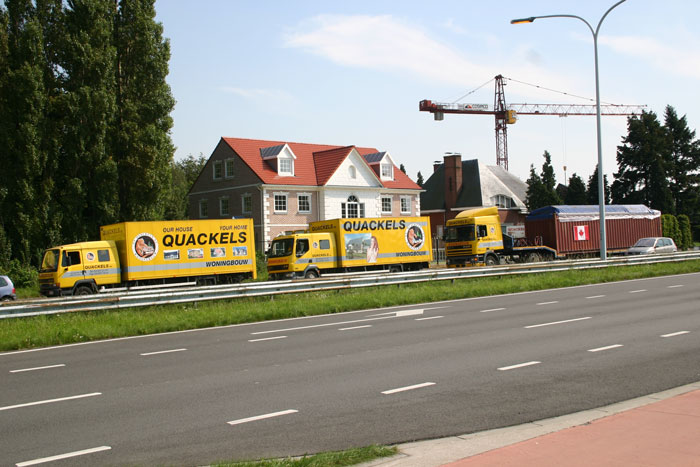 Vrachtwagens van het bouwbedrijf Quackels Woningbouw voor een woning in Amerikaanse bouwstijl