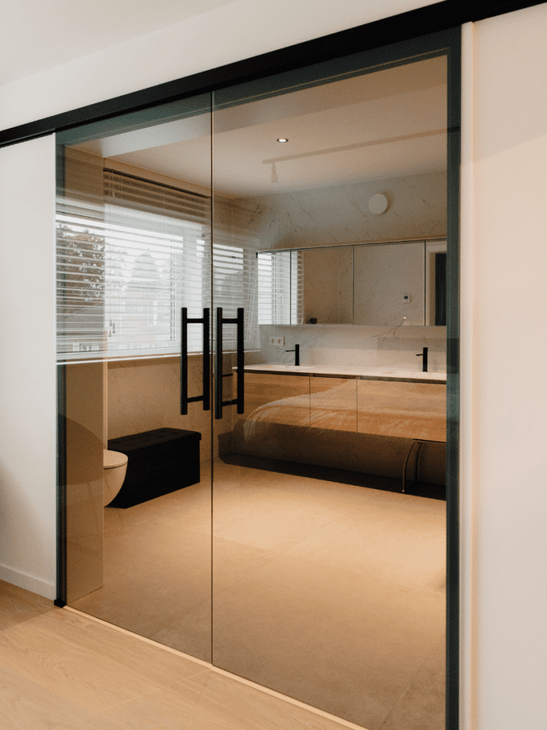 Zwarte, glazen schuifdeur van de badkamer in de master bedroom.