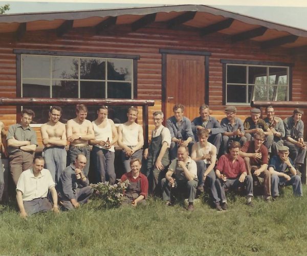 Werknemers van Quackels Woningbouw poseren voor een chalet in de Ardennen